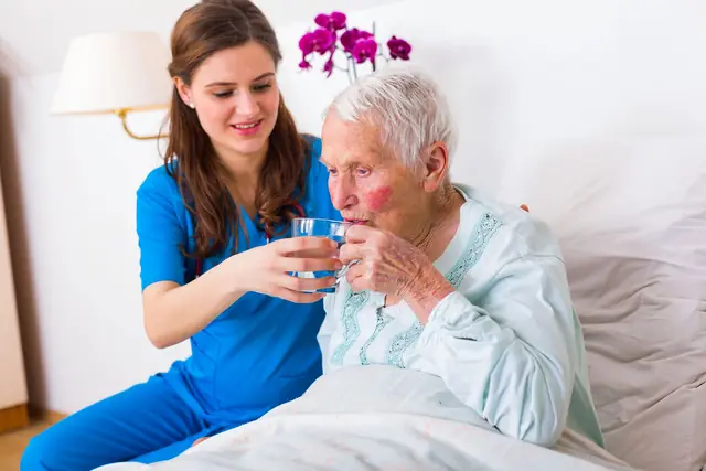 Home Caregiver Bringing Water To The Senior Woman 640