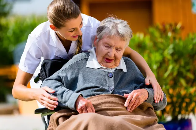 Why Choose Us A caregiver puts her arm around an older woman in a wheelchair in a garden