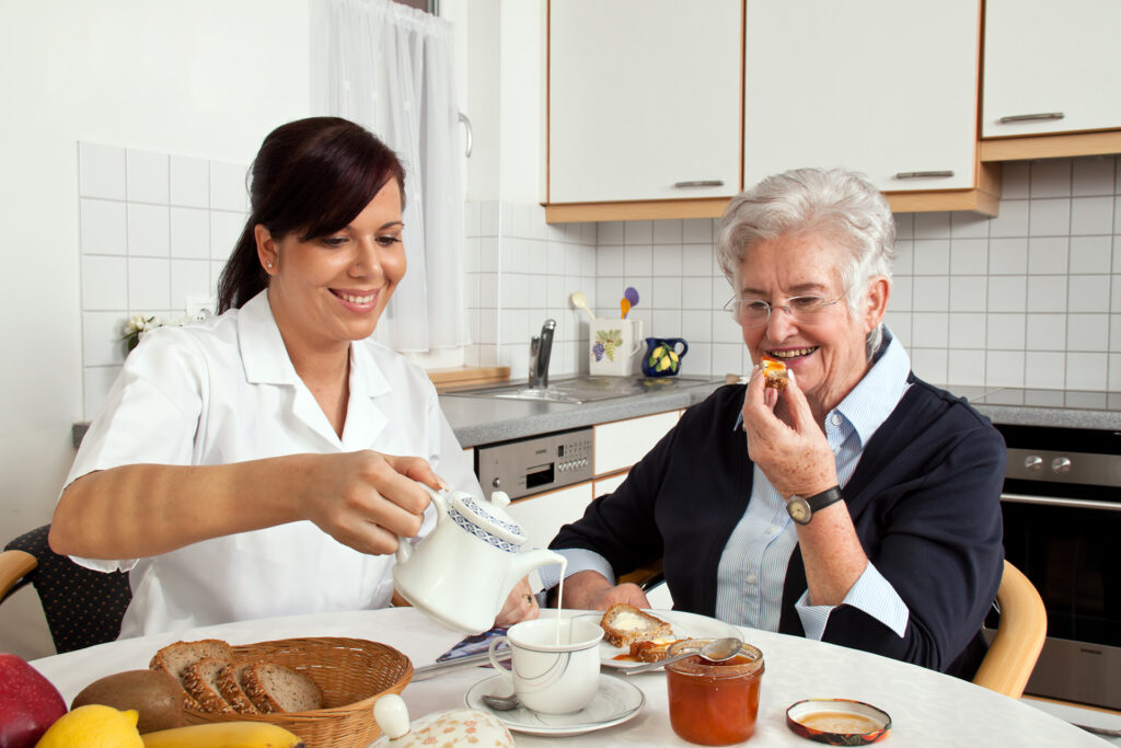 occupational therapy nurse helps elderly woman at breakfast